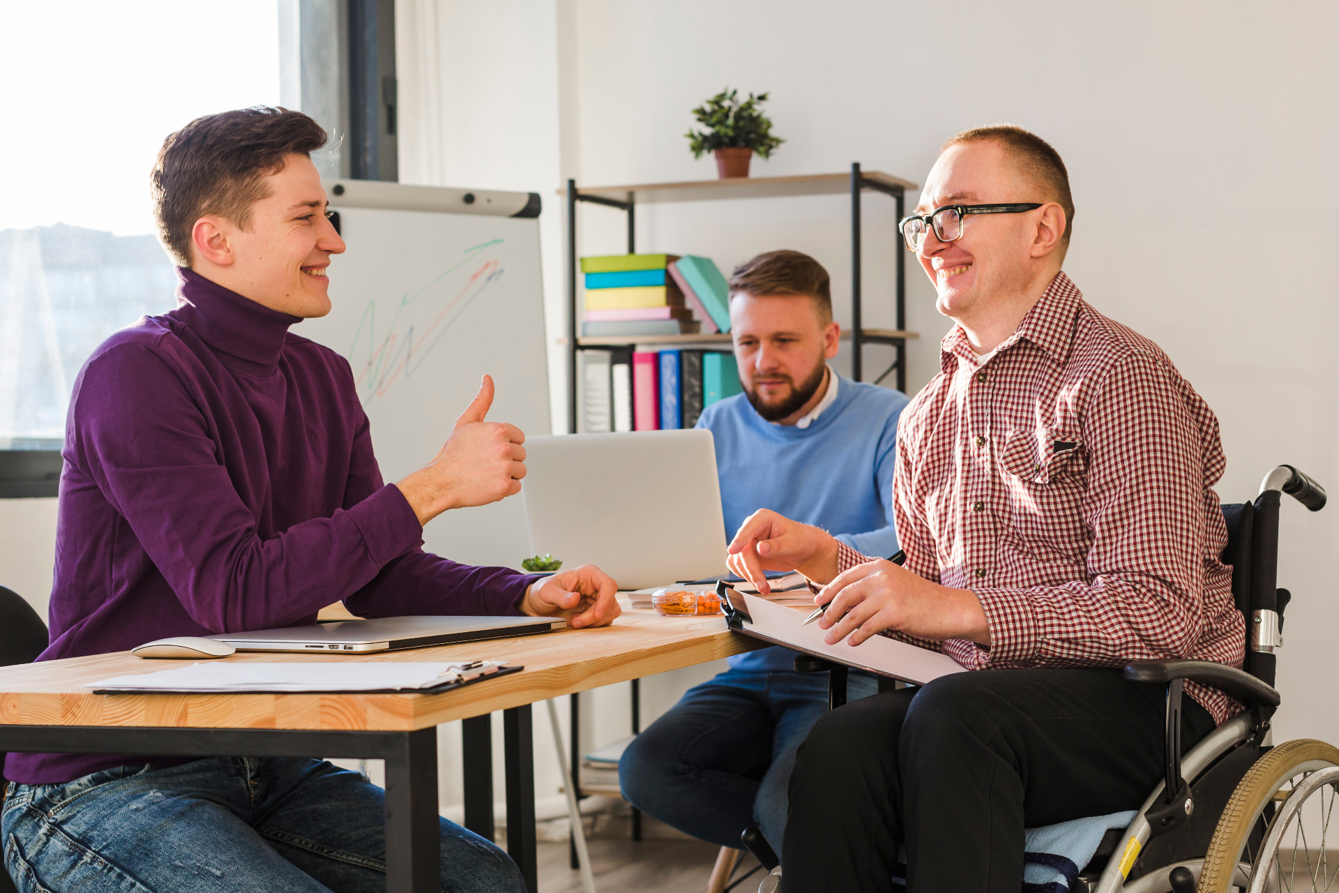 A workplace team collaborating, including a colleague who uses a wheelchair